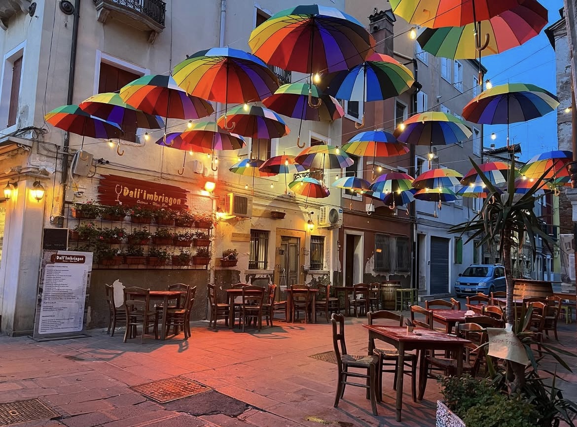 Bar sul canale con luci soffuse e atmosfera notturna a Chioggia