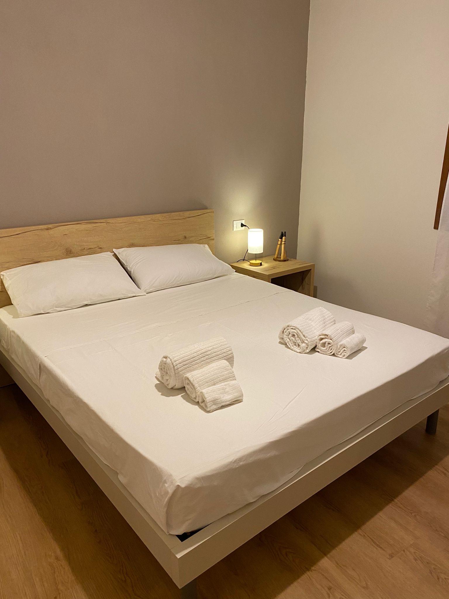 Camera beige e bianca con letto matrimoniale e luce naturale